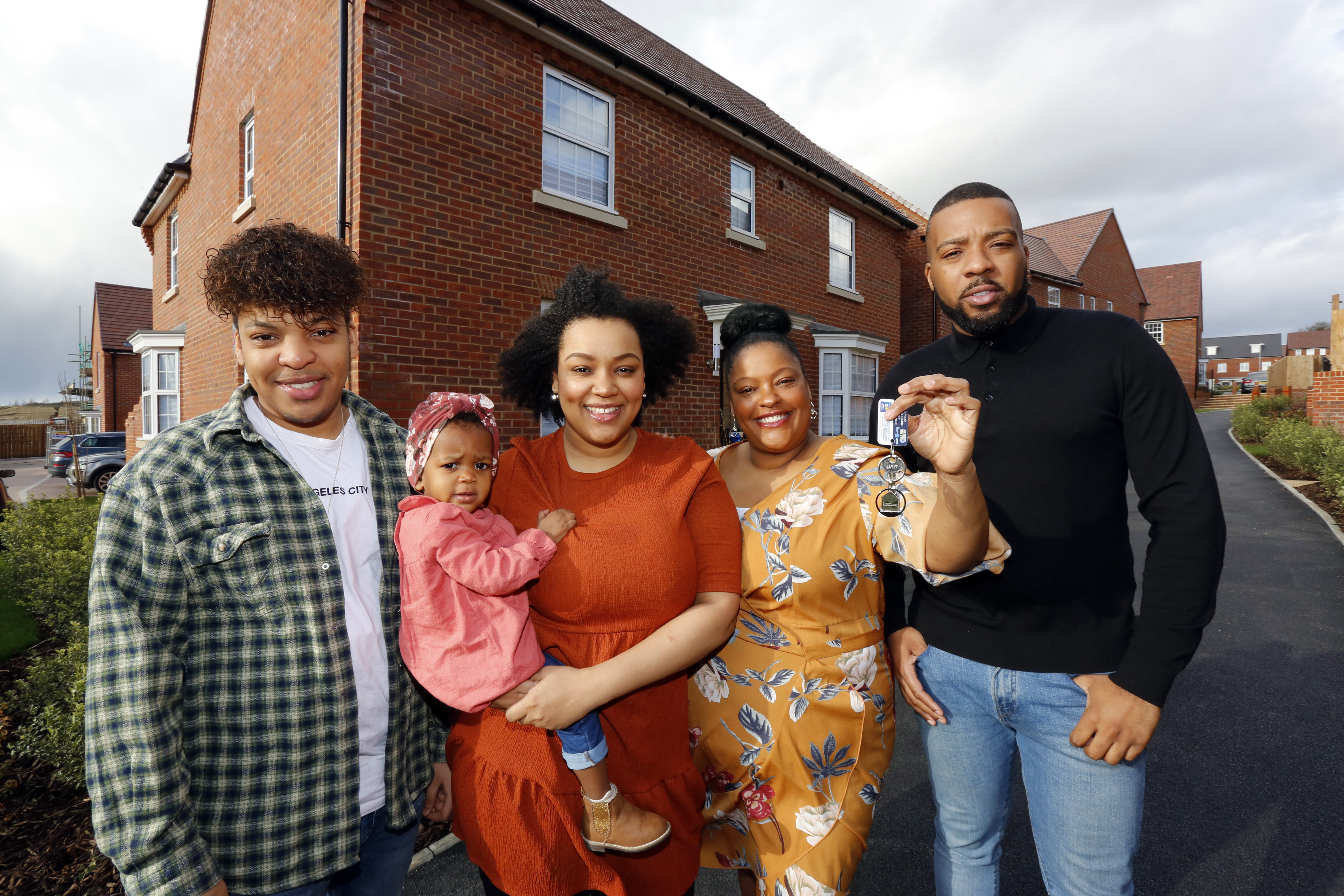 Image of family standing in front of new home holding keys to front door