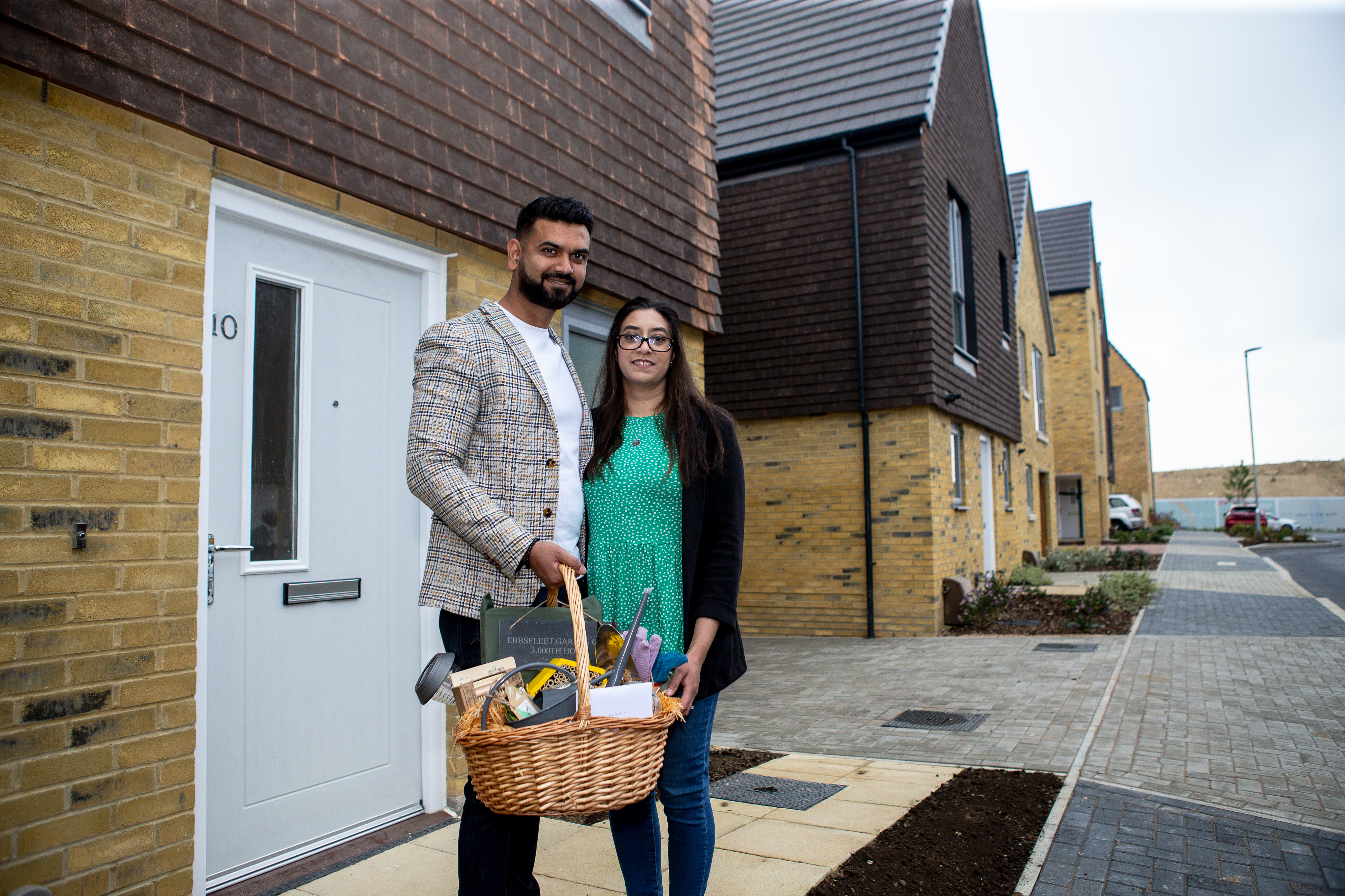 image of couple standing in front of new home with gift basket