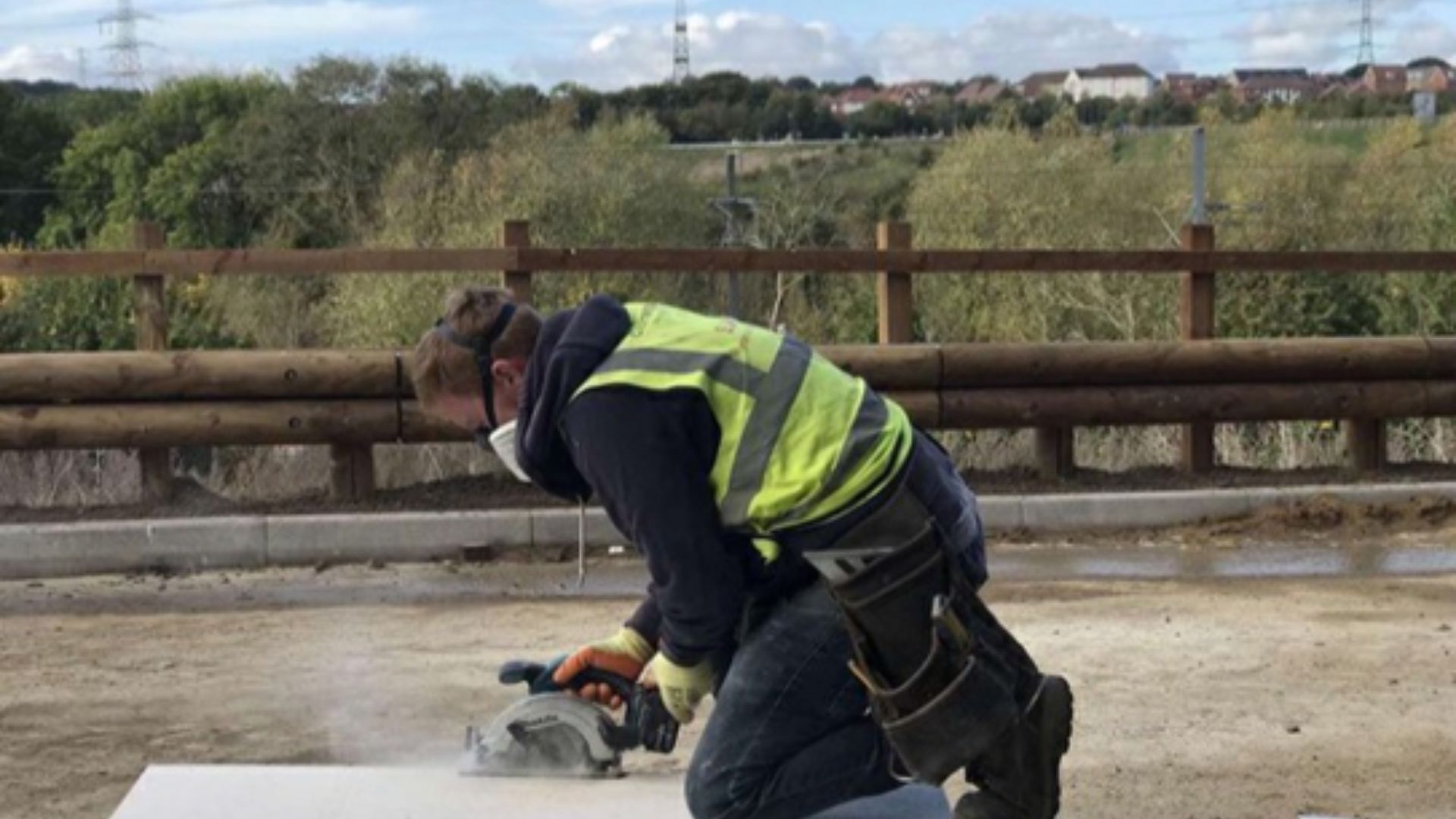 Image of male construction worker in hi vis cutting wood
