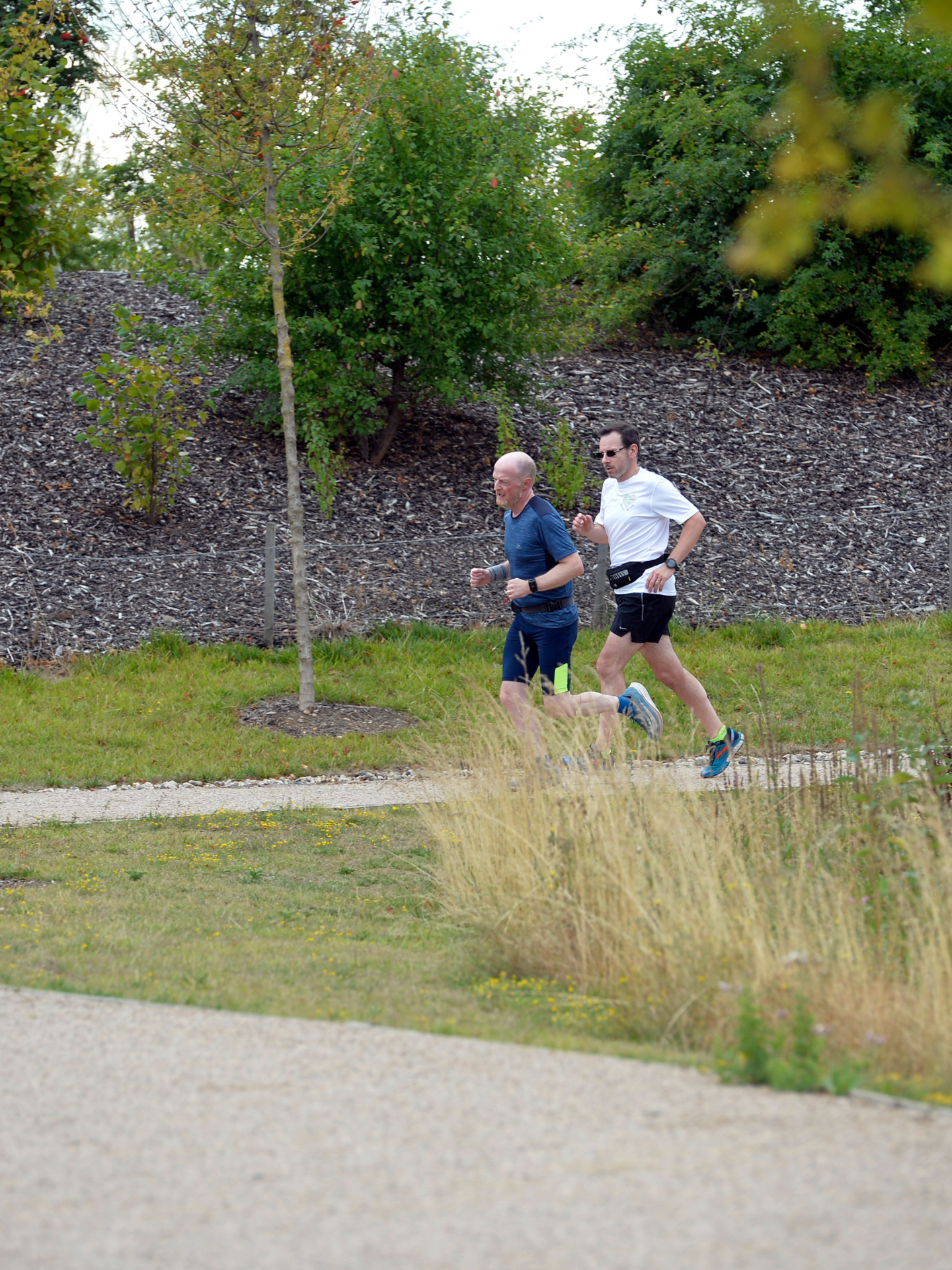 two men running on a path with shrubbery