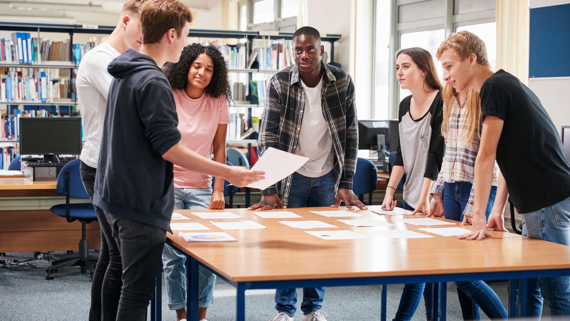 Stock image of students standing around a desk