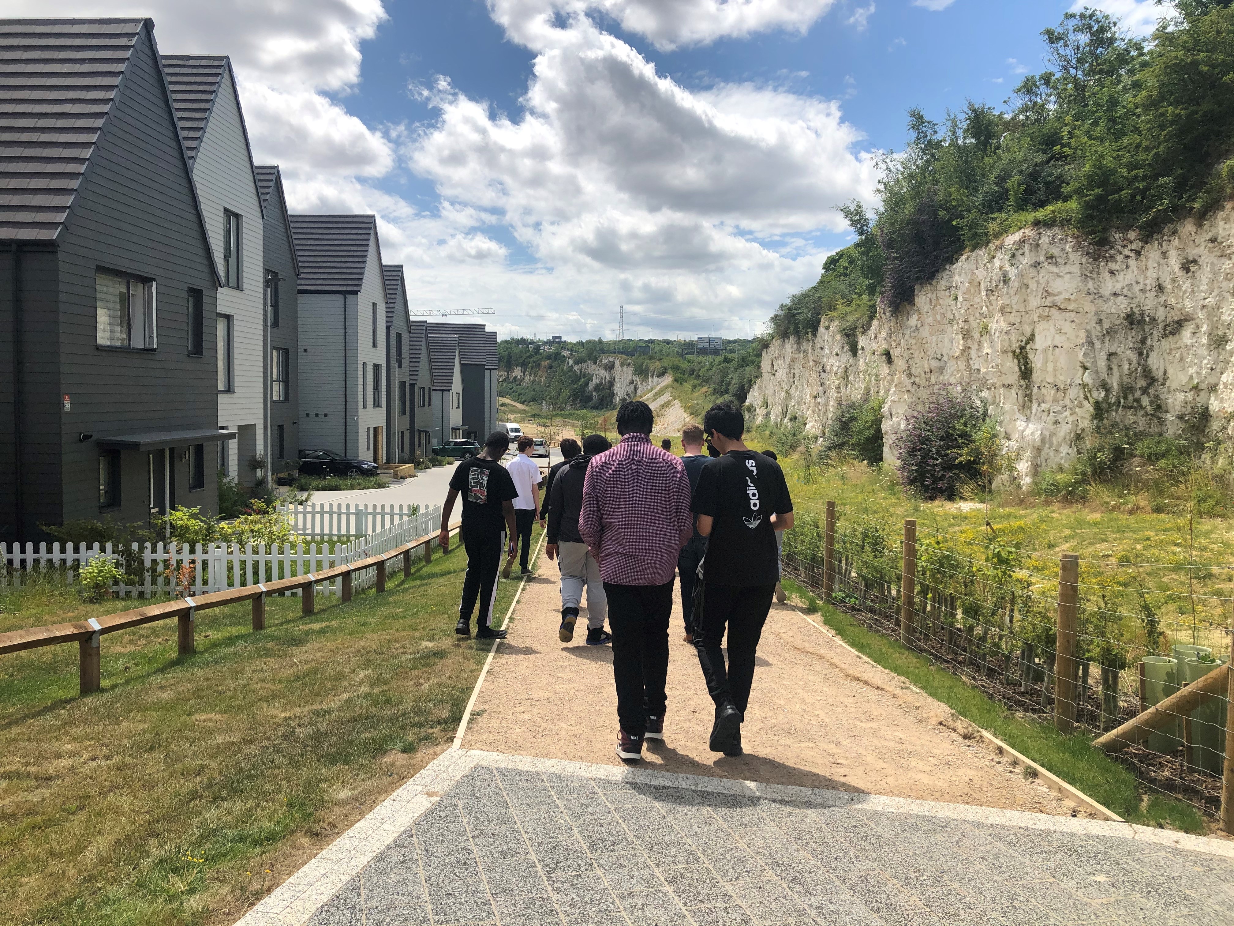 A group of teenage boys walking down path with houses and chalk cliff